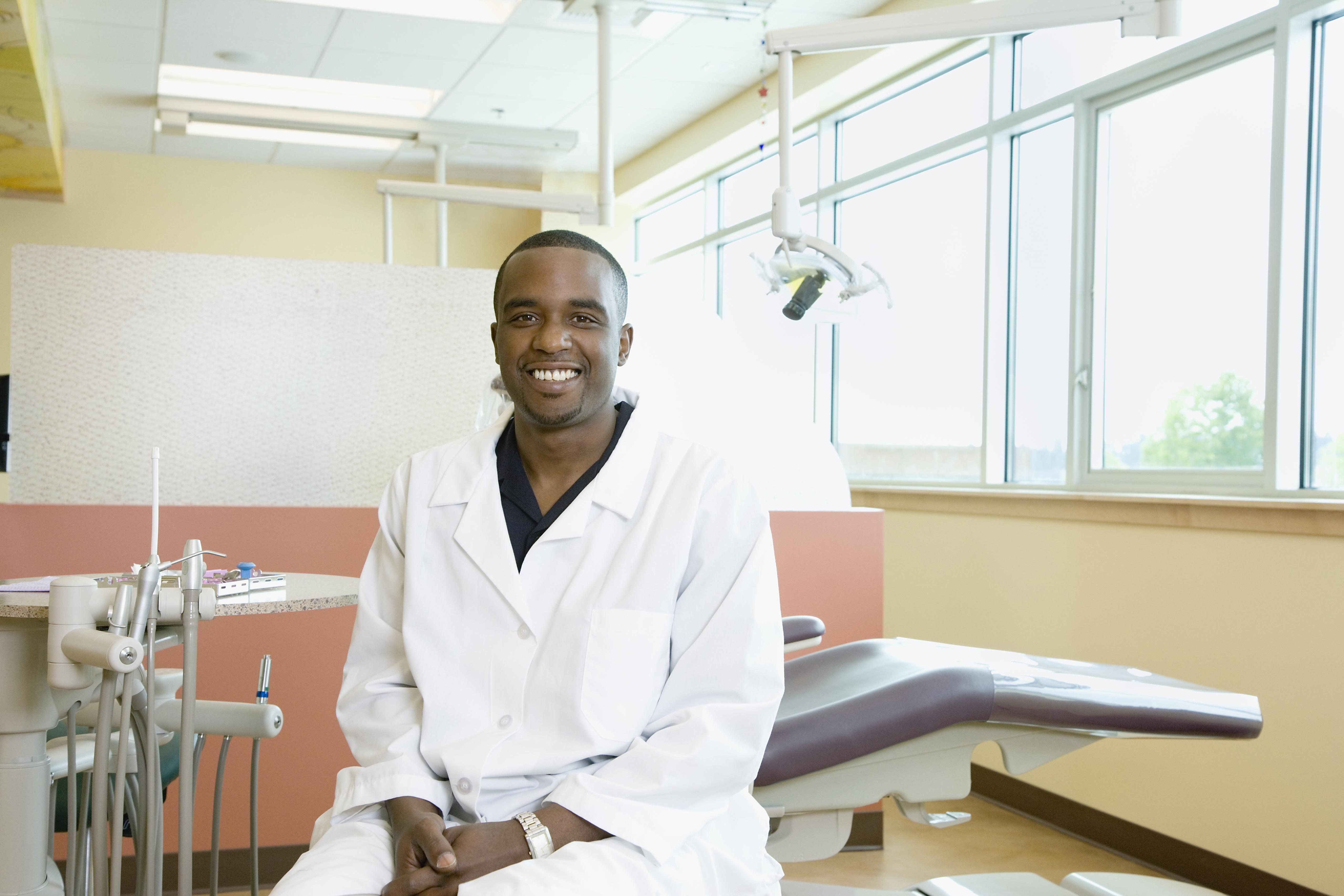 Male dentist sitting by dentist's chair, portrait