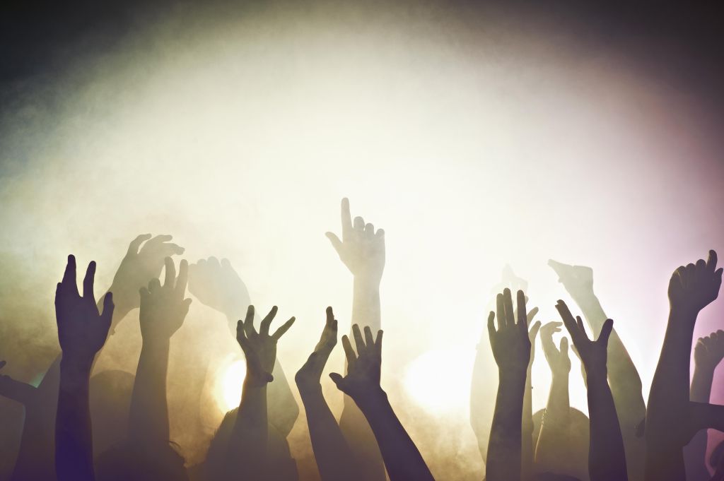 Crowd of people at concert waving arms in the air