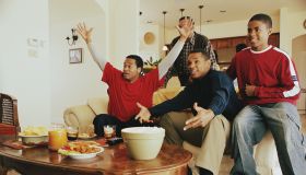 Three generations of men cheering in living room