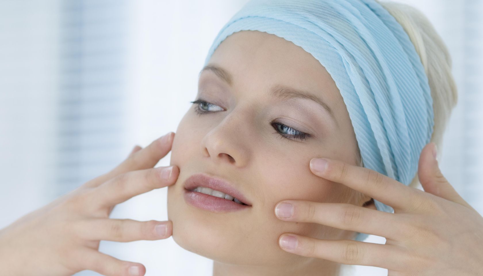 Young Woman face with make up, putting her fingers on her face, close-up (studio)