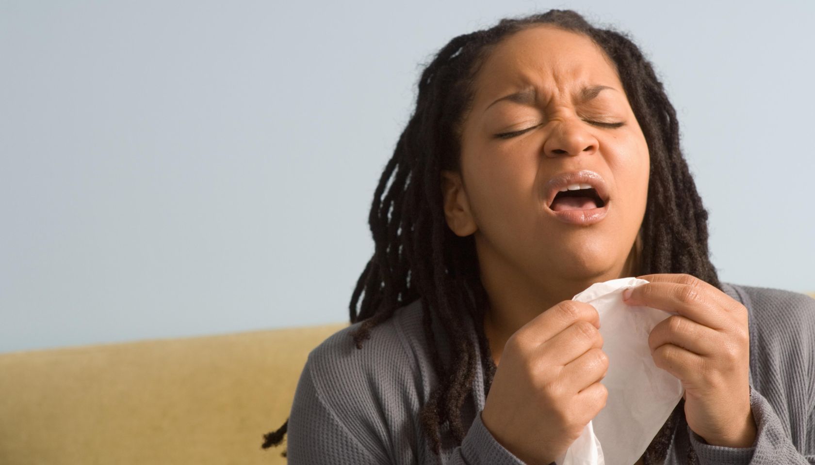 Woman preparing to sneeze into tissue, indoors