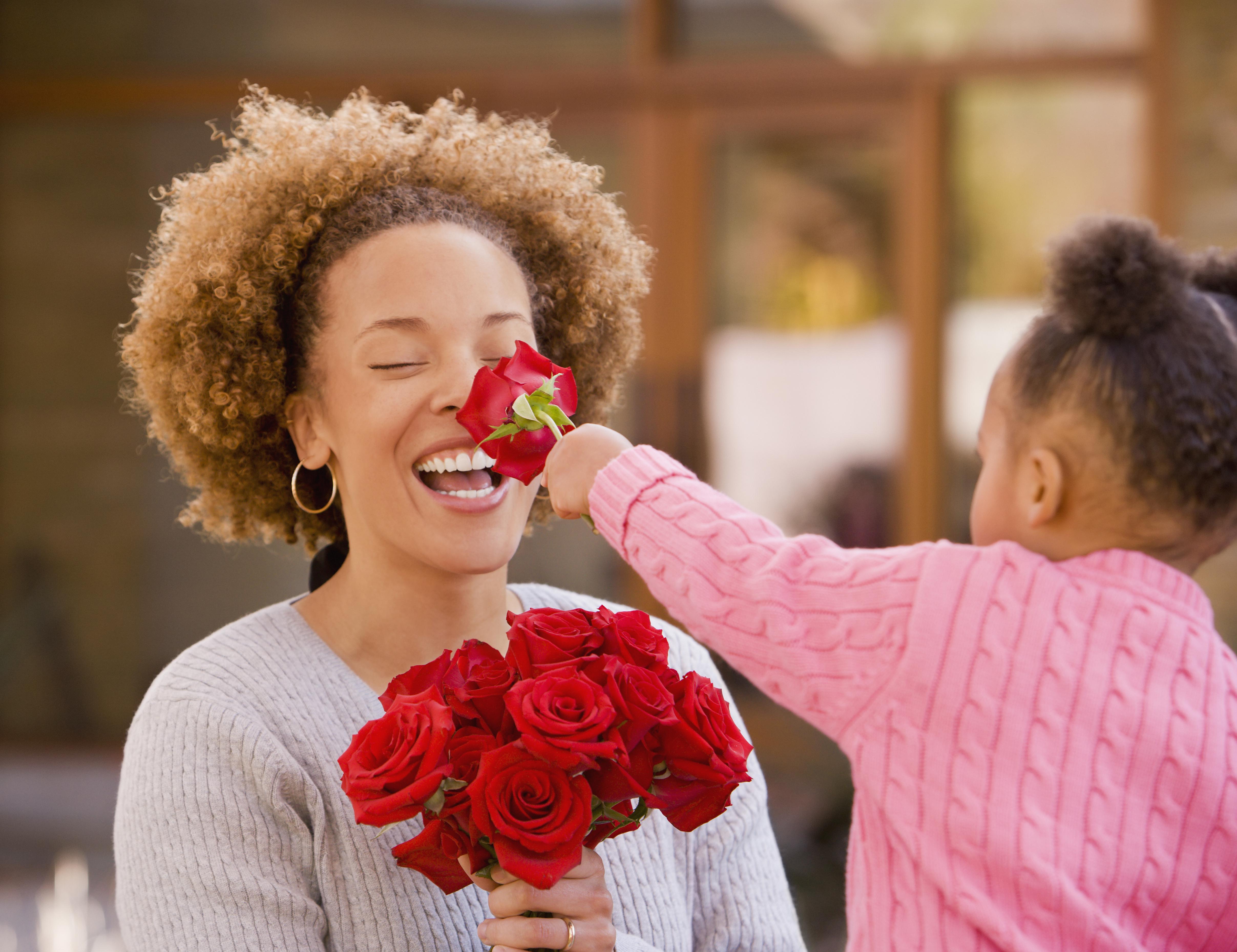 African girl giving flowers to mother