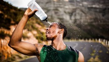 African American athlete splashing water on his face after excer