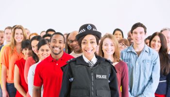 Portrait of smiling policewoman in front of large crowd