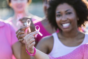 Multiracial women holding breast cancer awareness ribbon