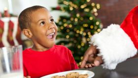 Surprised little boy sees Santa taking Christmas cookie