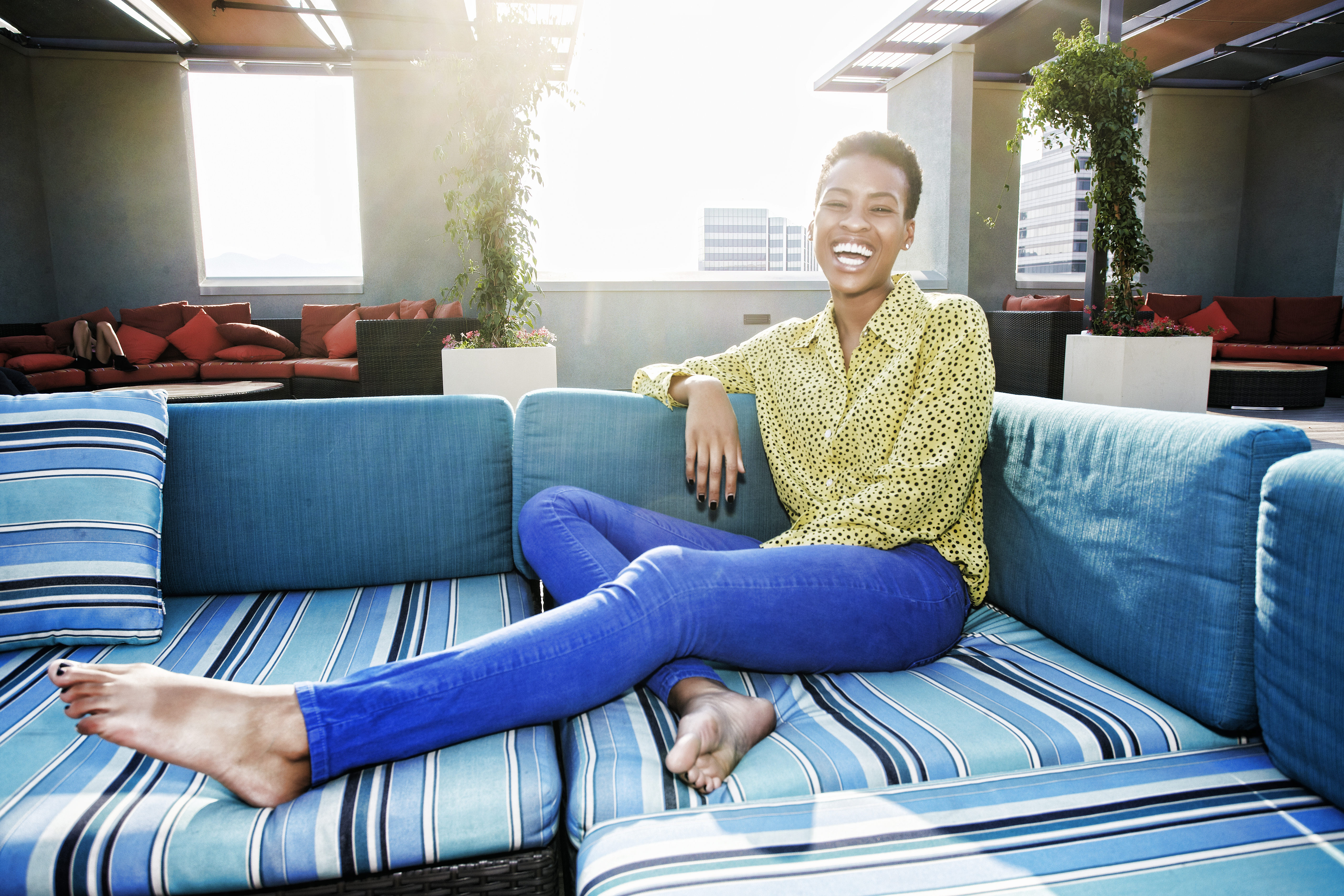 Black woman laughing on rooftop sofa