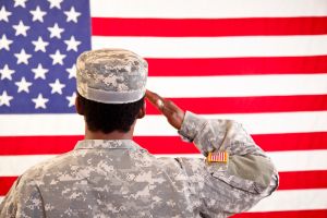 African descent woman in military uniform saluting American flag.