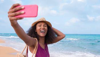 Happy free woman with positive emotion taking selfie on tropical beach.