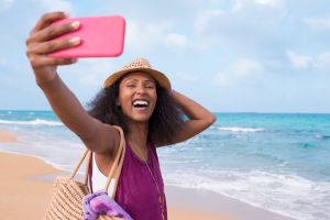 Happy free woman with positive emotion taking selfie on tropical beach.