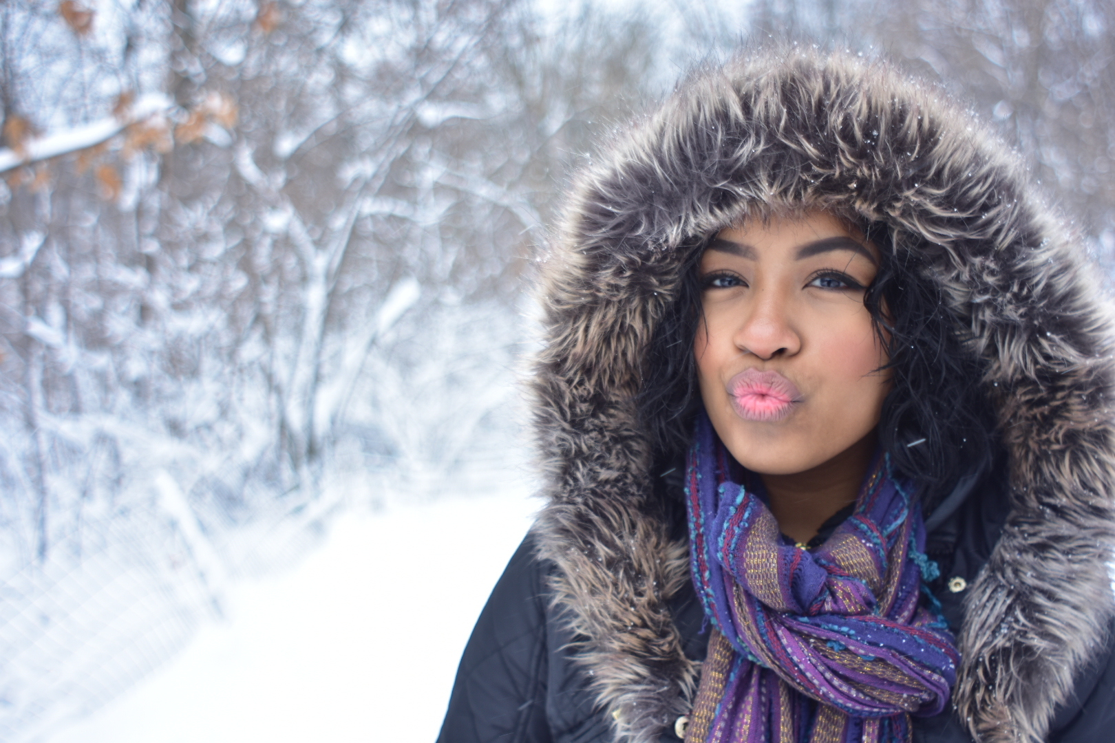 Portrait Of Woman Puckering Lips While Wearing Fur Jacket During Winter Season