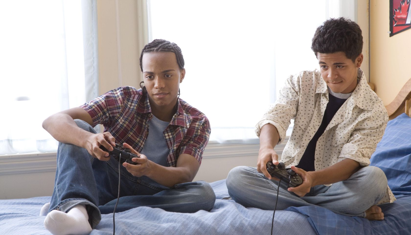Two teenage boys (16-17) playing video games on bed