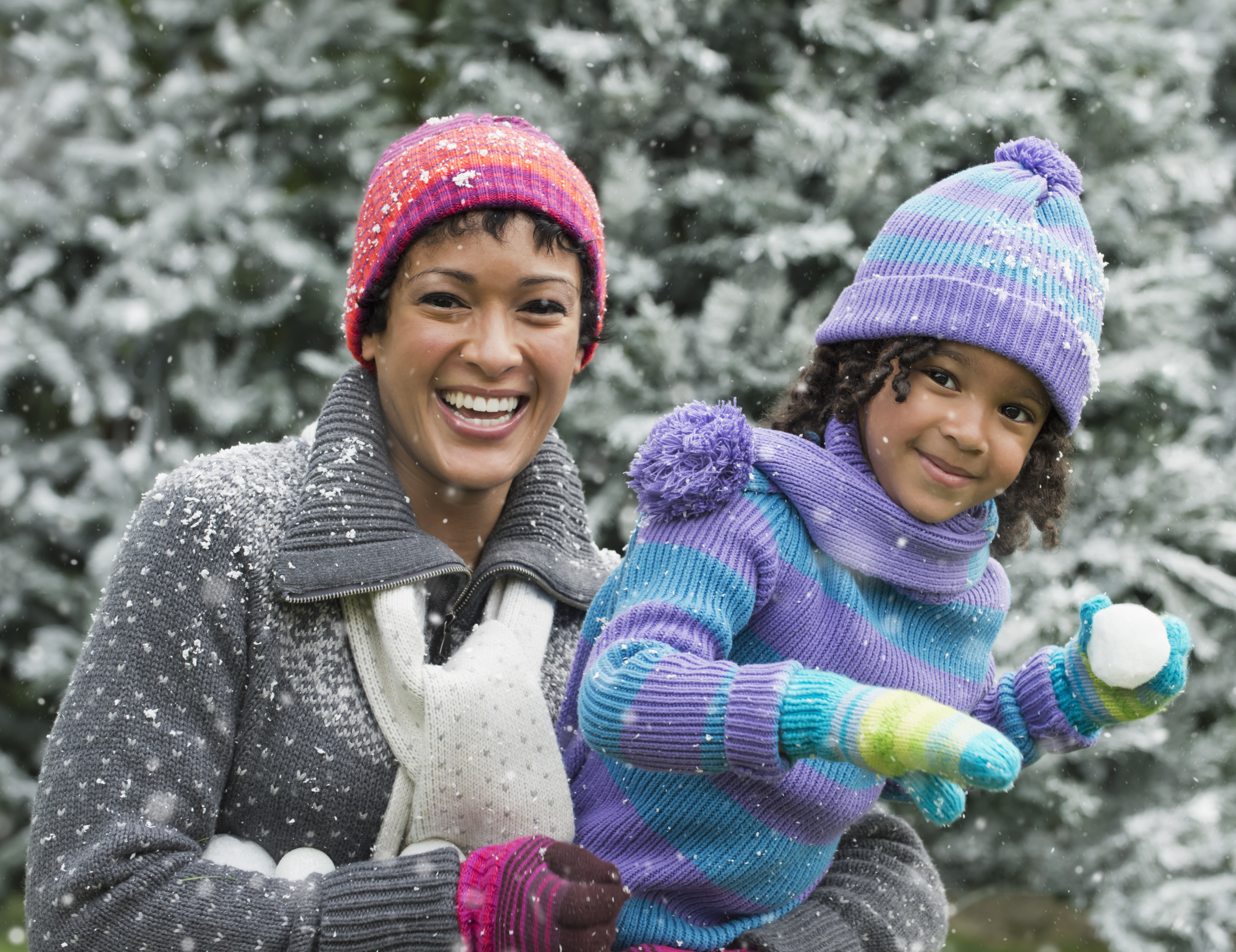 Black mother and daughter having a snowball fight