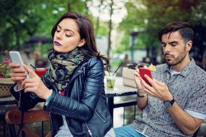 Couple is looking in their mobile phones and sulking each other in the cafe