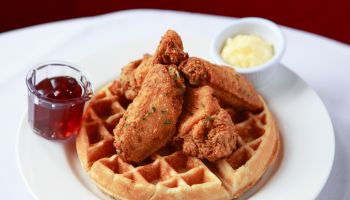 fried chicken and waffles on restaurant table with syrup and butter