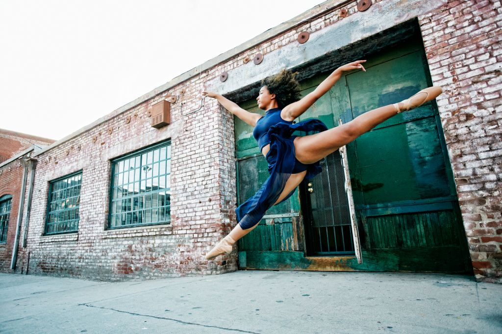 Mixed race woman dancing ballet in city
