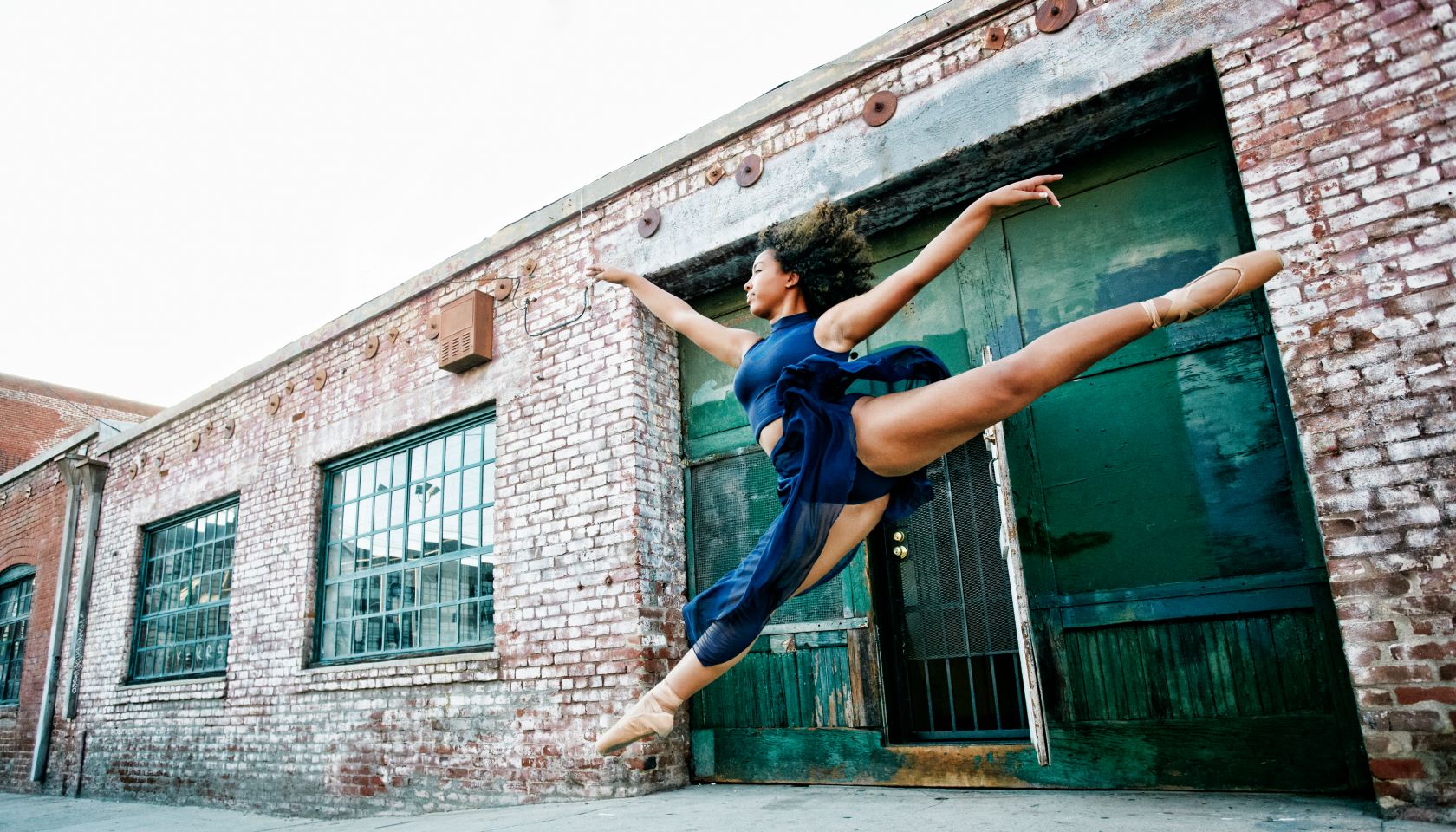 Mixed race woman dancing ballet in city