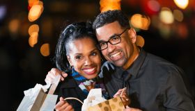 Happy black couple opening a gift bag outdoors at night