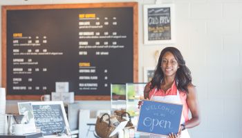 Proud coffee shop owner hold open sign on first day of business