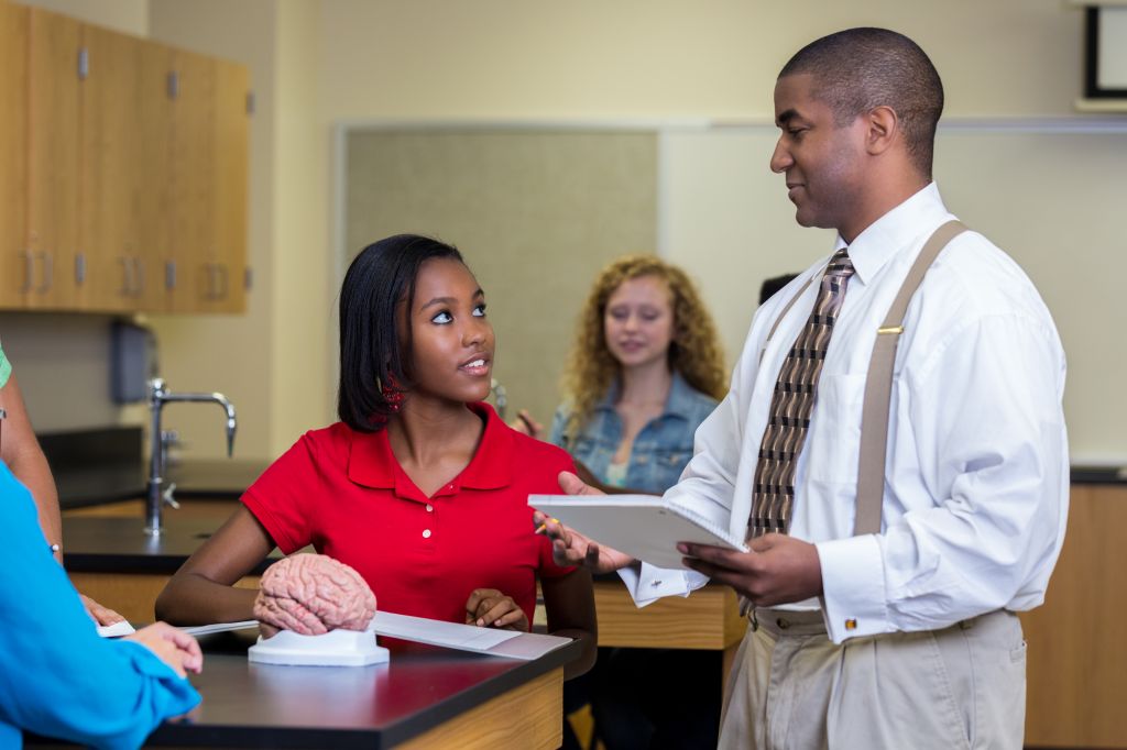 African American high school science teacher works with students