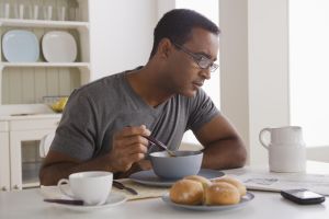 USA, California, Los Angeles, Mature man eating breakfast and reading newspaper
