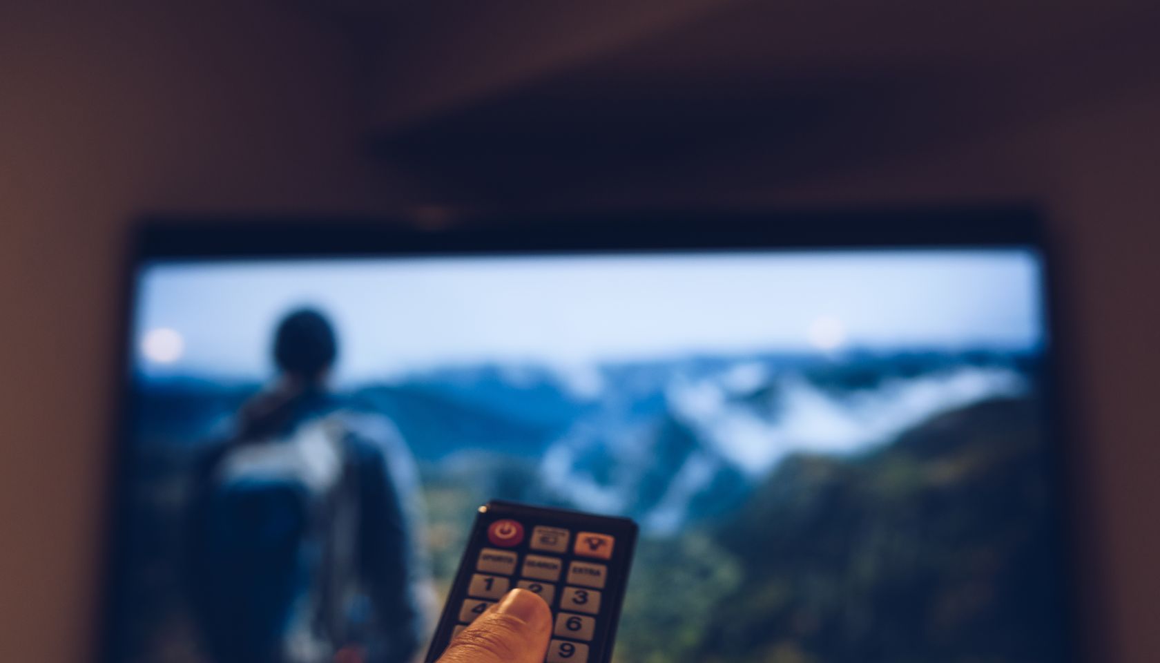 Cropped Image Of Hand Holding Remote Control In Front Of Television Set