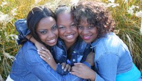 Three African American girlfriends hugging
