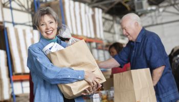 Happy mature woman holding groceries at food pantry