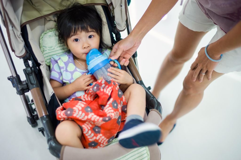 Toddler girl drinking water in stroller