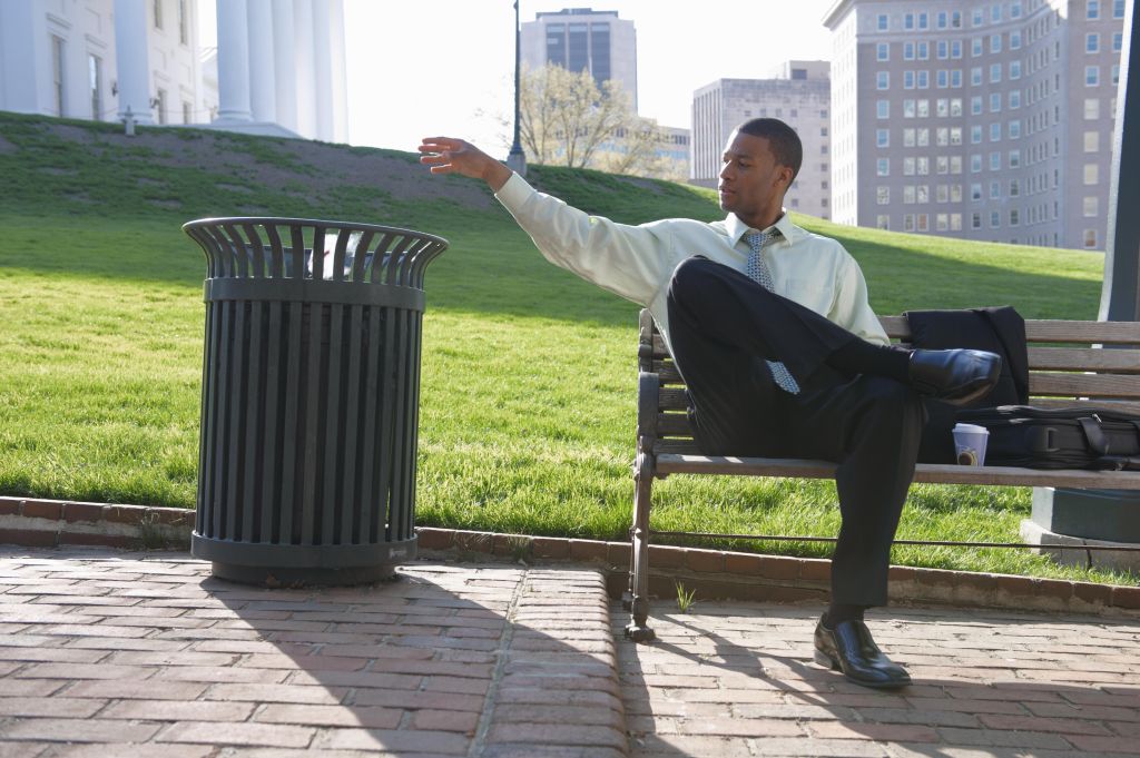 African American businessman throwing trash in garbage can