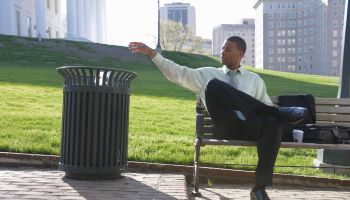 African American businessman throwing trash in garbage can