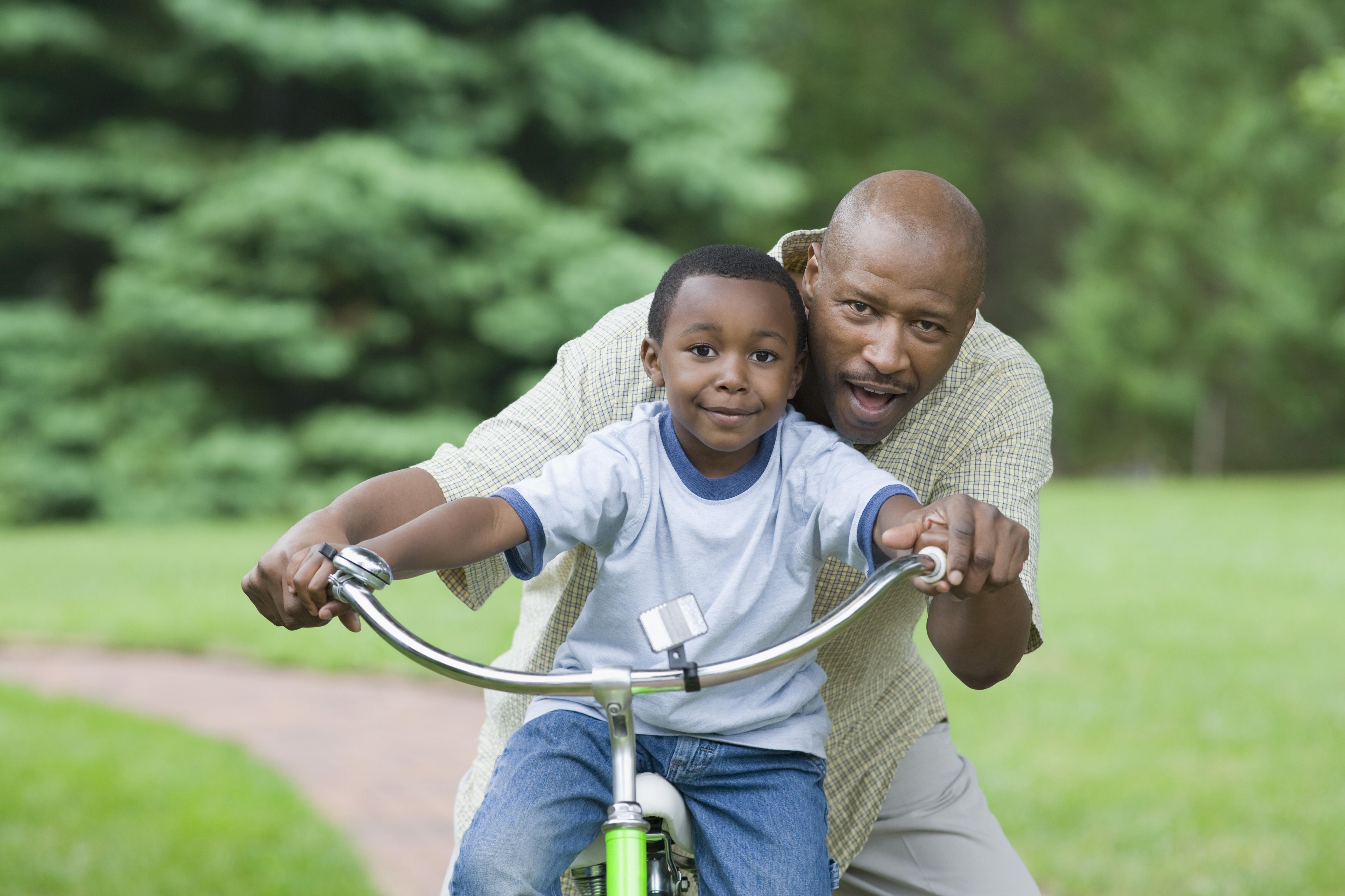 Portrait of a mid adult man teaching his son to how to ride a bicycle