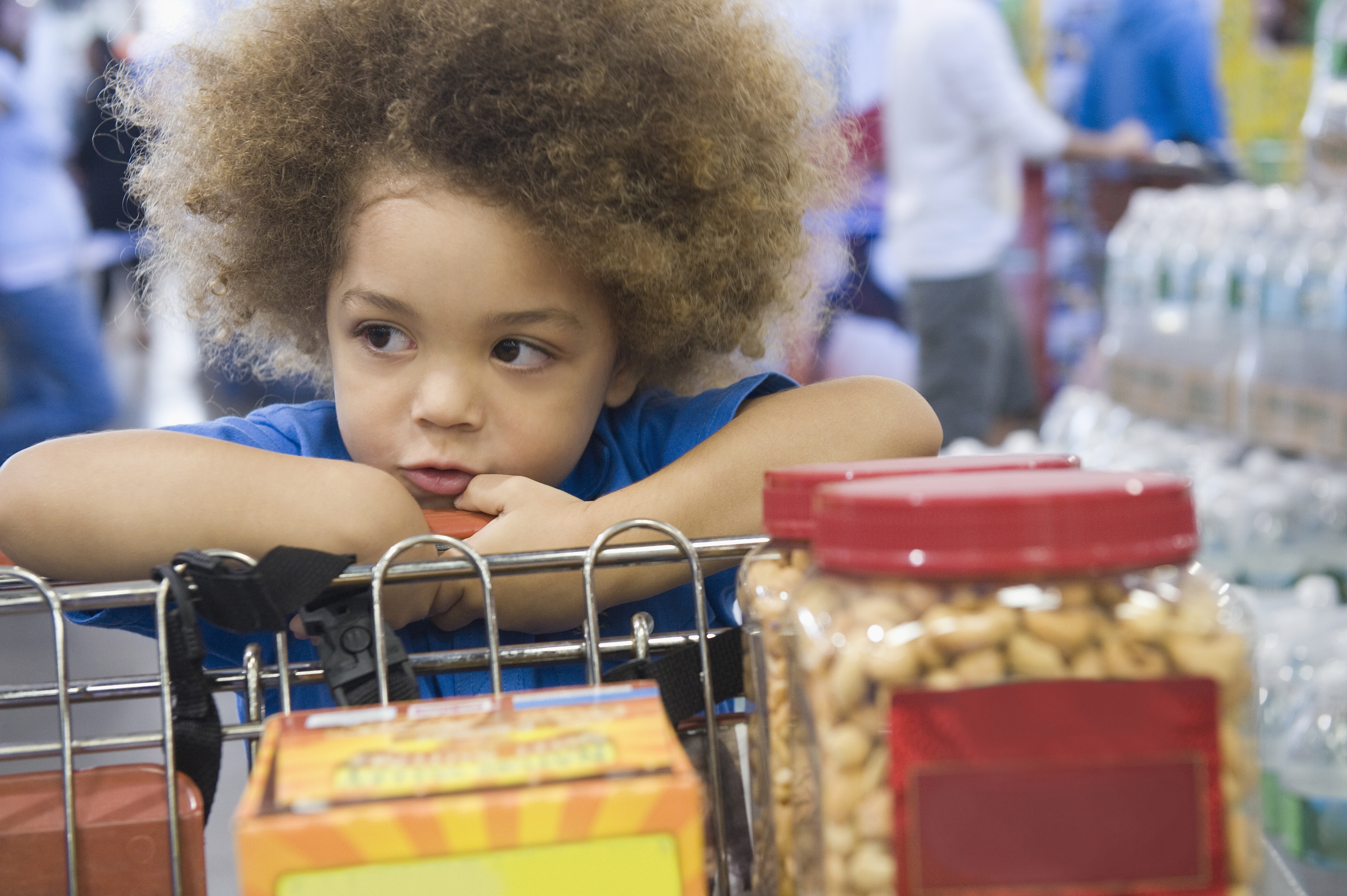Mixed race boy sitting in shopping cart