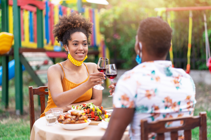Afro Couple wearing protective face mask having staycation romantic dinner on back yard, during COVID-19