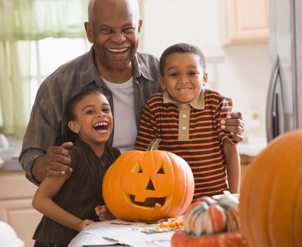 Grandfather and grandchildren carving a pumpkin