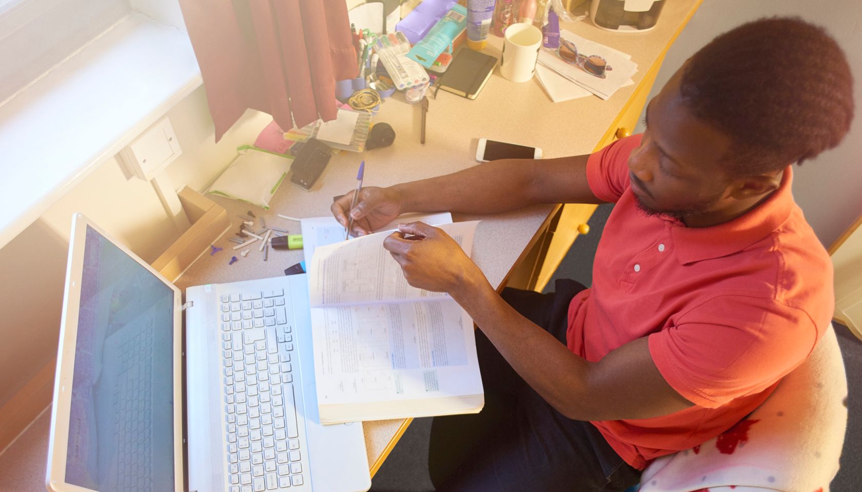 Male university student studying in his room at uni