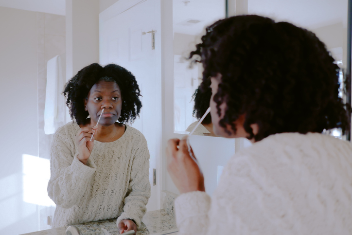 Woman Uses Cotton Swab to Collect Nasal Sample for At-Home COVID-19 Test