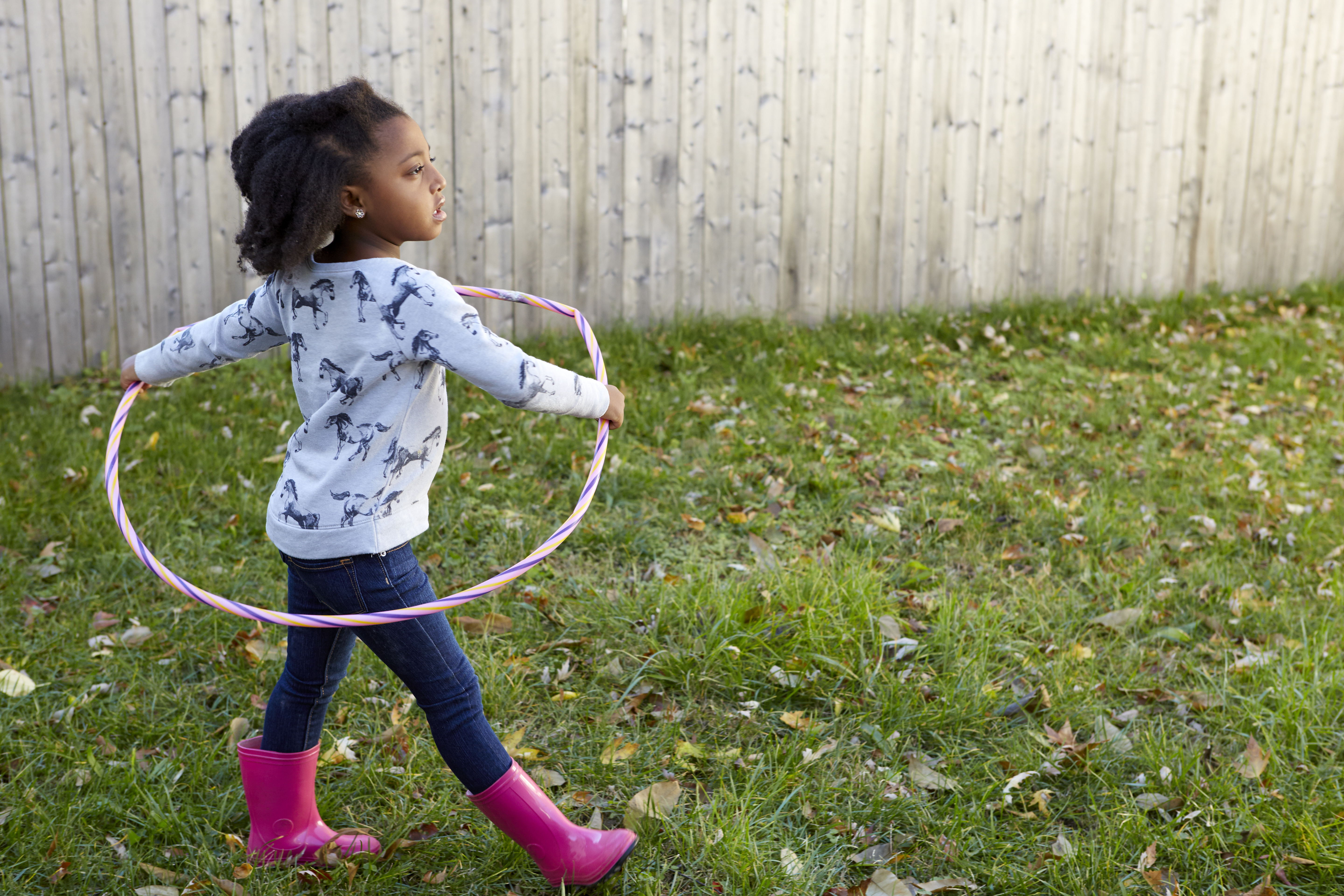 Cute girl playing in garden with plastic hoop