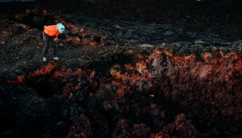 A woman looks into a deep hole that formed in a volcanic lava flow in Hawaii