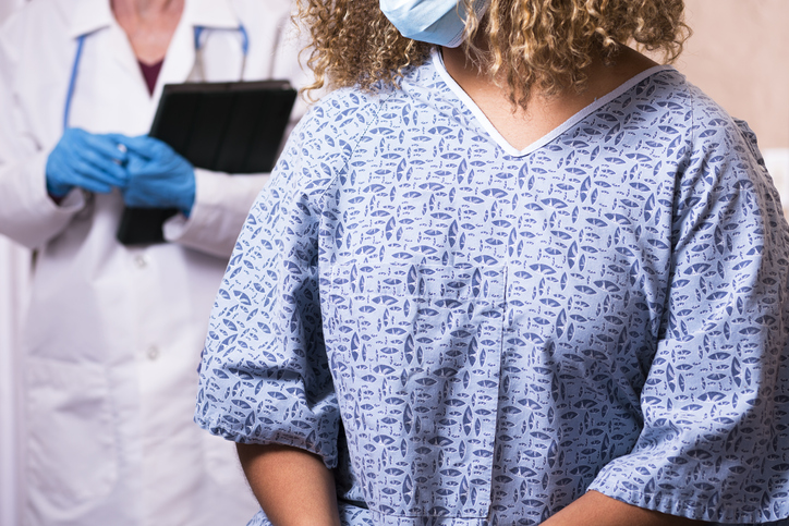 Young African American Woman prepares for breast exam, mammogram at doctor's office or hospital.