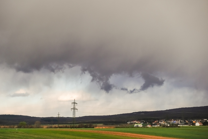 heavy gray rain clouds over a nature landscape with forest houses