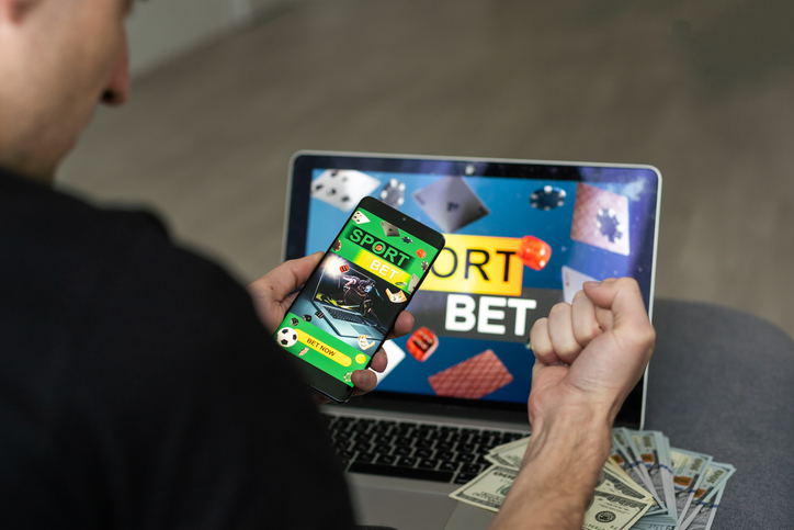 Man watching football play online broadcast on his laptop, cheering for his favourite team, making bets at bookmaker's website