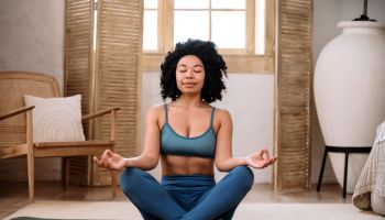 Relaxed woman in sportswear closed eyes, practicing yoga