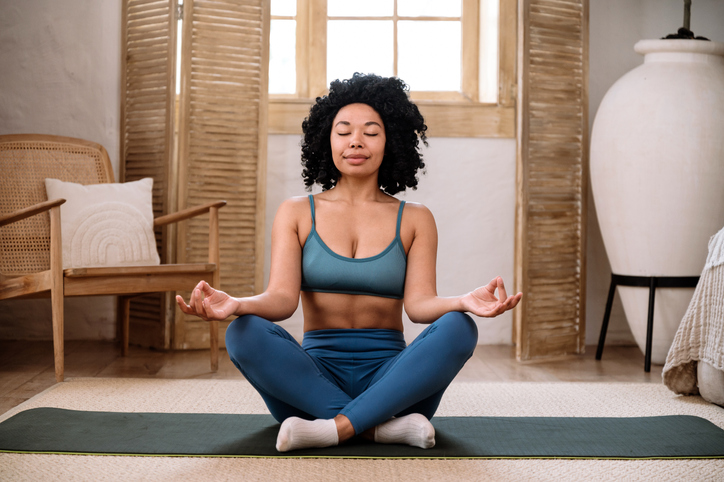Relaxed woman in sportswear closed eyes, practicing yoga