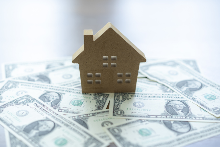 Wooden house on a stack of dollar money banknotes. Property loan concept