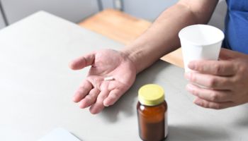 Hand of an Asian senior man taking medicine
