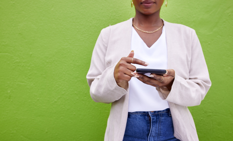 Hands, internet and phone for communication by a wall or green background for connection. Closeup of a woman with a smartphone for social media search, networking and mobile app chat or mockup space
