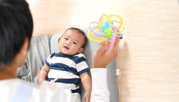 Rear view of a man soothing an Asian baby with a toy
