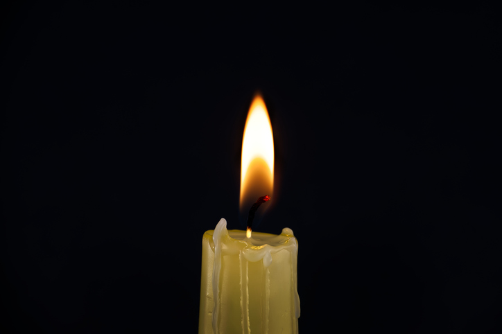 Single burning candle over black background
