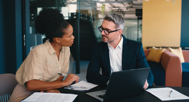 Business meeting, people or talking at laptop for advice, feedback or brainstorming in office. Man, woman or tech in workplace for performance review, discussion or problem solving for company growth